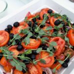 Blandet salat med tomat, oliven, rødløg, sesamfrø og garniture.